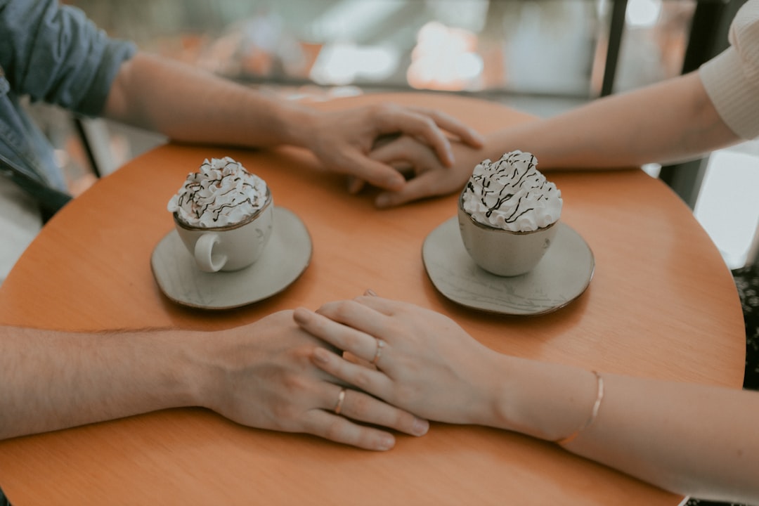Zwei Menschen halten bei einem Date ihre Hände über Kaffee